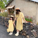 فستان صيفي متناسق للأم والابنة بنقش المربعات باللون الأصفر الفاتح، وأكمام متوسطة الطول وياقة واسعة