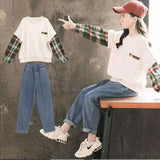 A two-piece set for girls, a white T-shirt-style sweater with long sleeves in a check pattern and denim pants.