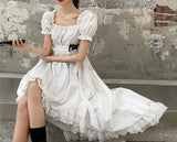 White dress with a square chest, puff sleeves, a short end in the front and a long end in the back, and a lace edge