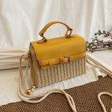 A solid straw crossbody bag with a square shape, a leather cover and handle, and an elegant front strap and shoulder rope