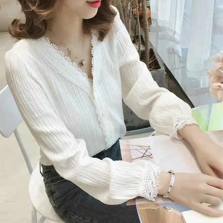 A white women's top with a triangle opening, long sleeves, and decorated with lace at the edges