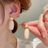 an elegant gold colored earring with pearls and decorated with a beautiful pink color