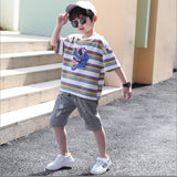 A two-piece set for a boy, a white T-shirt with contrasting stripes and a dinosaur face print , and khaki torn denim shorts with front pockets