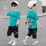A two-piece boy's set: a wide T-shirt with a cartoon character printed on the back and writing, and long black shorts with an X sign on the sides
