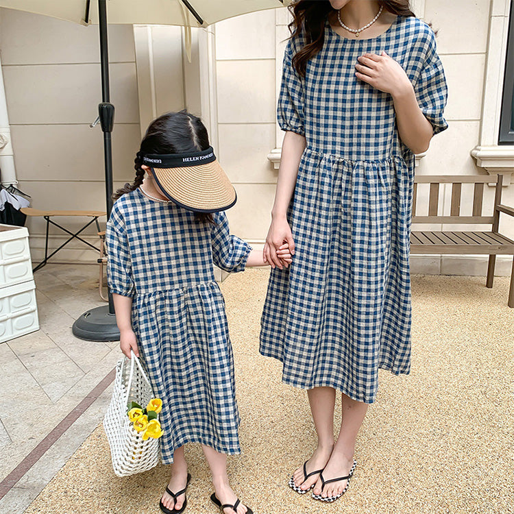 A mother and daughter set of two matching dresses in a black and white check pattern with midi sleeves
