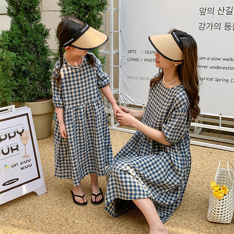 A mother and daughter set of two matching dresses in a black and white check pattern with midi sleeves