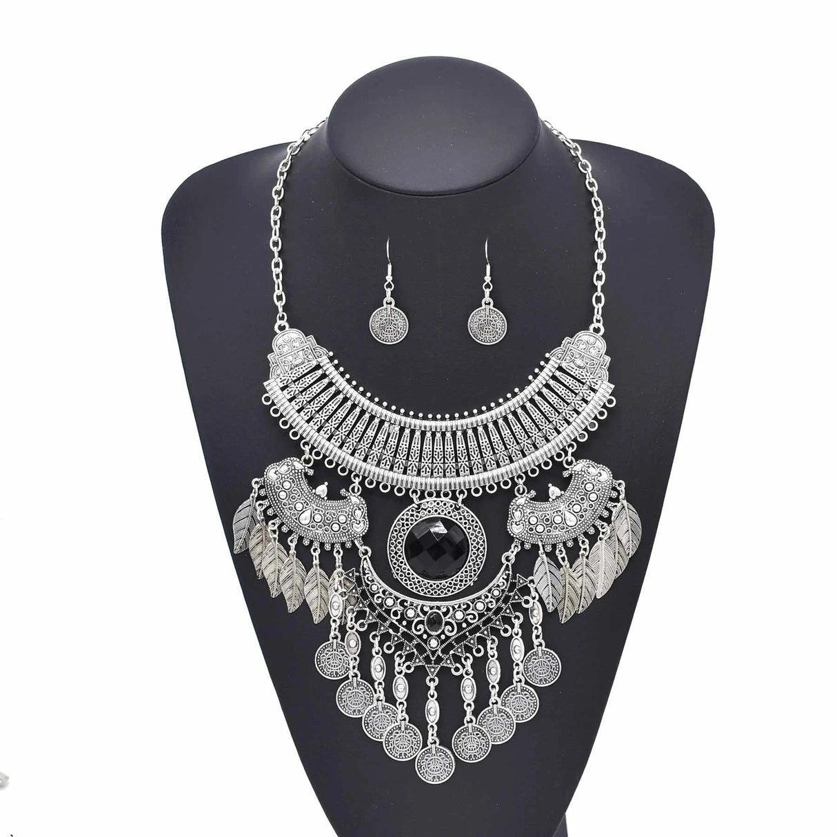 silver colored bohemian women's accessory set of two pieces, earrings and a large three-tiered chain with a large central black stone, and dangling coins and leaves.