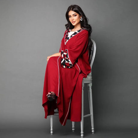 A red galabiya with two longitudinal white stripes, long sleeves, and a neckline with an interlaced border