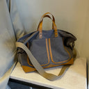 Large capacity women's canvas bag with a wide shoulder strap, handles and two front pockets with leather borders