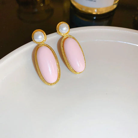 an elegant gold colored earring with pearls and decorated with a beautiful pink color