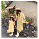 فستان صيفي متناسق للأم والابنة بنقش المربعات باللون الأصفر الفاتح، وأكمام متوسطة الطول وياقة واسعة
