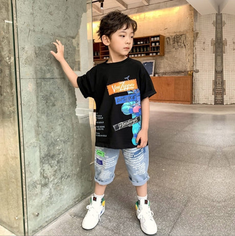 Two-piece boy's set: a wide T-shirt with colorful phrases printed and light-colored denim shorts with many phrases printed