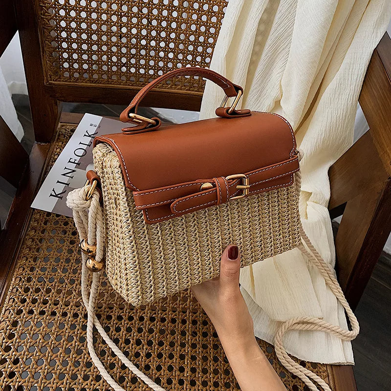 A solid straw crossbody bag with a square shape, a leather cover and handle, and an elegant front strap and shoulder rope
