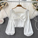Elegant women's blouse with longitudinal stripes of cut-out lace, a heart-shaped neckline and long puffy sleeves