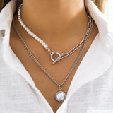 A necklace set of two pendants, a pendant necklace, a half-pearl necklace, a half-ring and a T-clasp.