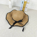 A summer straw hat decorated with a thin black ribbon and a bow