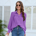 A plain, wide women's shirt with ruffles at the chest area, long puff sleeves and buttons on the front