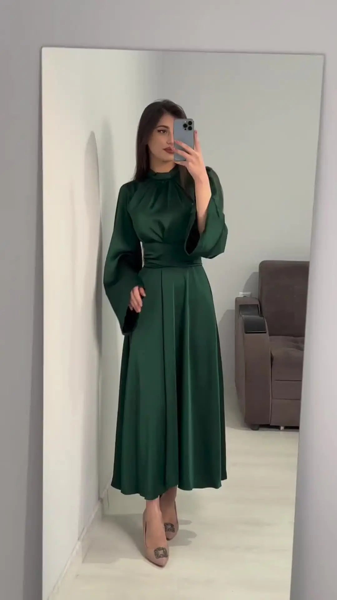 Long, soft dress in a solid color with a closed round neck, long puffed sleeves at the shoulders, and a wide waist belt
