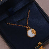A gold-colored necklace decorated with a moon and sun pendant