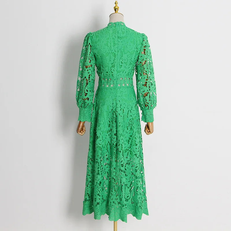 فستان طويل منسوج من قماش أخضر مقصوص، وأكمام طويلة، وأكتاف منتفخة، ورقبة دائرية مغلقة