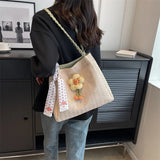 A summer shoulder bag decorated with a rose and a braided shoulder strap