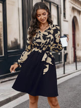 Short dress with an overlapping pattern with a black lower half, long sleeves and a waist belt