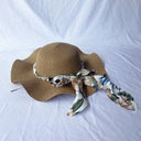 Women's summer straw hat with wavy brim and brim And a ribbon with a tree print around the circumference of the head
