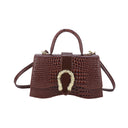 Small handbag in shiny snakeskin pattern with a solid color wavy bottom and a button strap closure