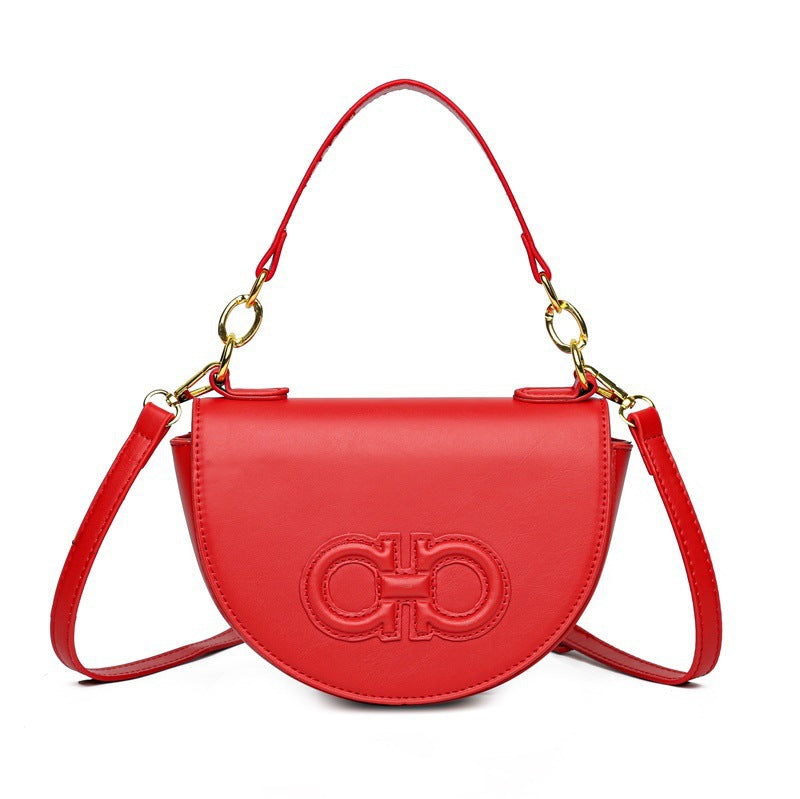 A small semicircular leather crossbody bag in a solid color with a stitched leather logo in the same color