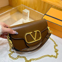 Solid color leather handbag with a large gold logo and an gold shoulder chain