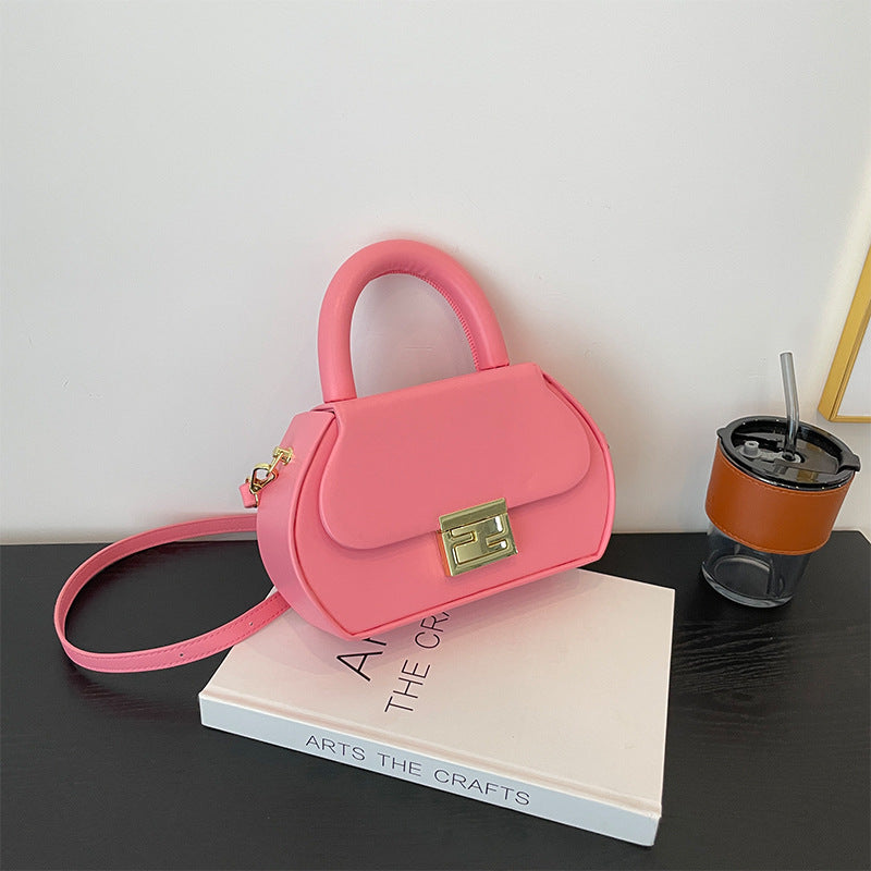 Fashionable solid color leather crossbody bag with elegant gold button closure and curved handle