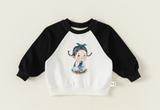 white pullover rounded nick and black sleeves , with a cartoon girl printed