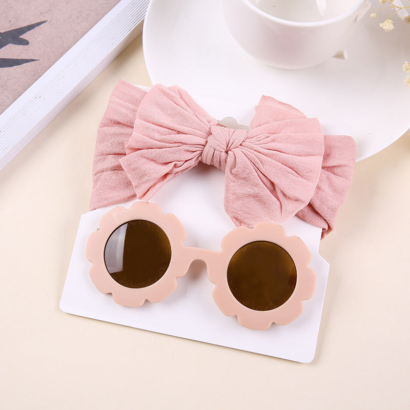 A grube of two sets, sunglasses with a rose-shaped frame and a bow headband in a solid color